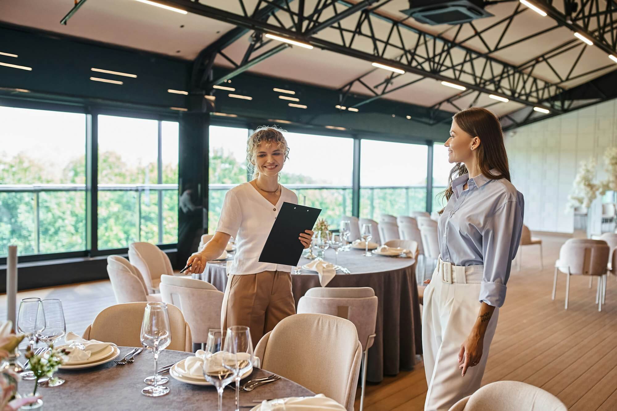 event-organizer-with-clipboard-pointing-at-table-with-festive-setting-near-woman-in-banquet-hall.jpg event-organizer-with-clipboard-pointing-at-table-with-festive-setting-near-woman-in-banquet-hall.jpg